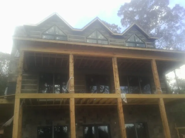 Dormers and porch framing on a large log home under construction — Roof Coating work by our crew in Selmer