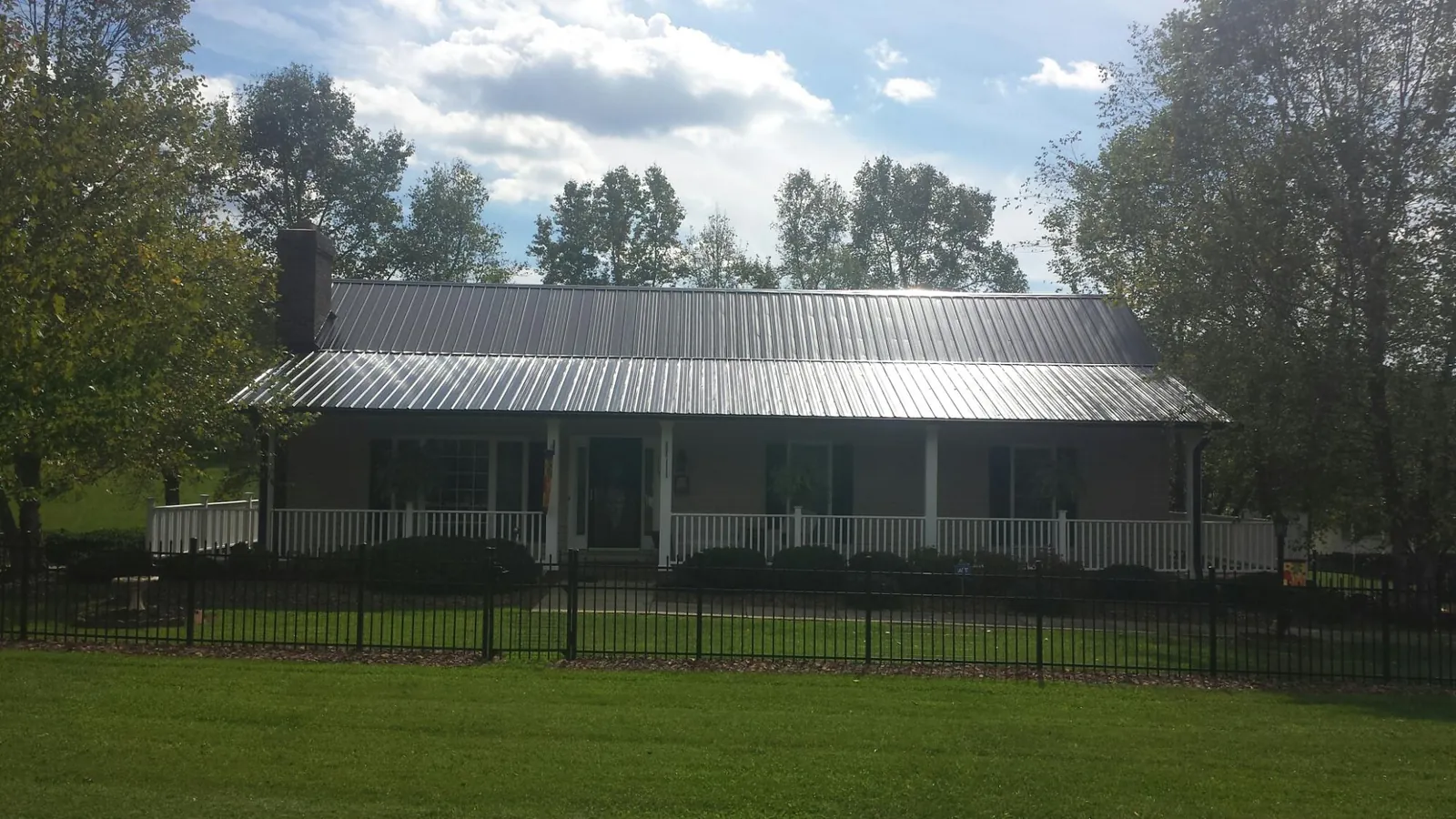 Gray metal roof on a brick ranch with a full width front porch — Gutter Guard Installation work by our crew in Selmer