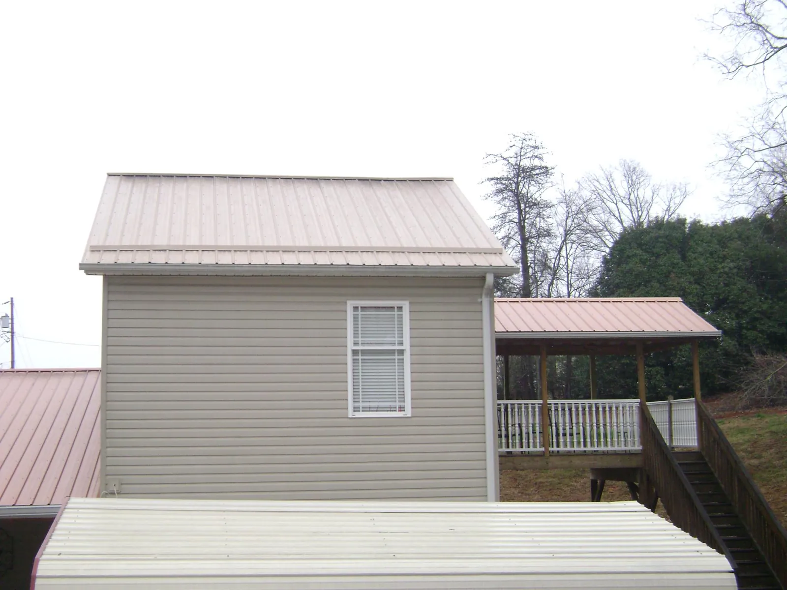 Tan metal roofs on a two story addition and attached porch, from a Roof Replacement job in Selmer