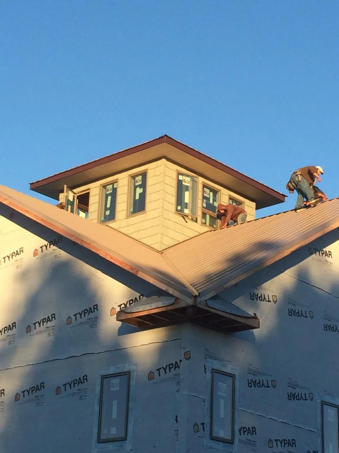 Roofers working around a rooftop cupola on a new metal roof at sunset — Roof Waterproofing in Selmer by Roofing Brothers